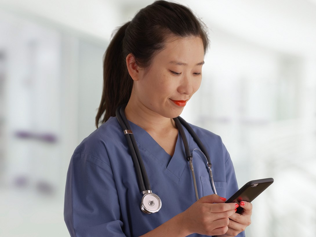 Kvinnlig sköterska tittar på en smartphone