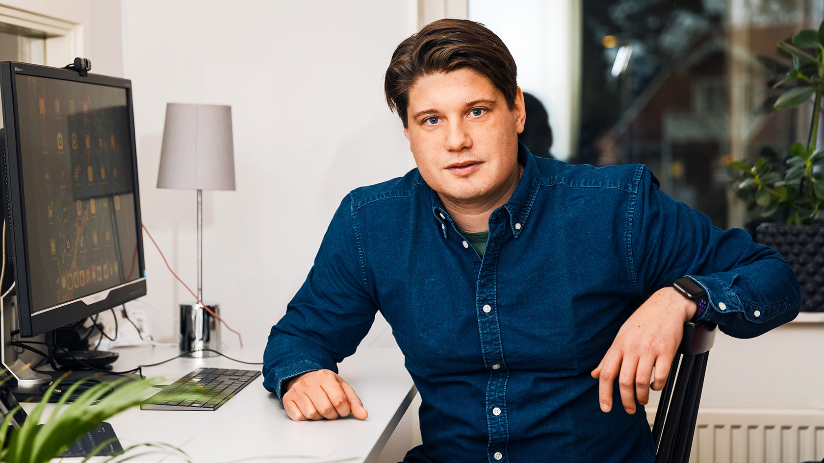 Jesper sitter vid hemmakontor och tittar mot kameran