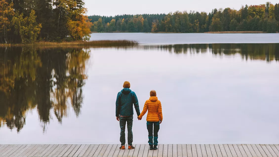 Man och kvinna håller händerna och tittar ut över sjö