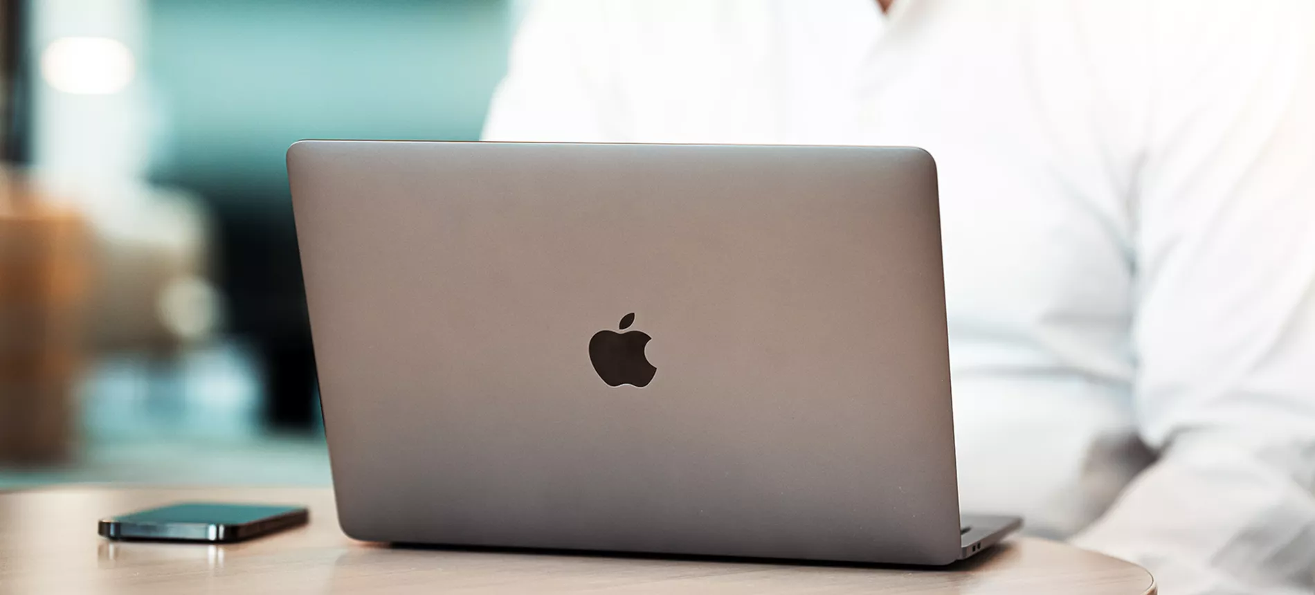 En Macbook och iPhone liggandes på ett bord