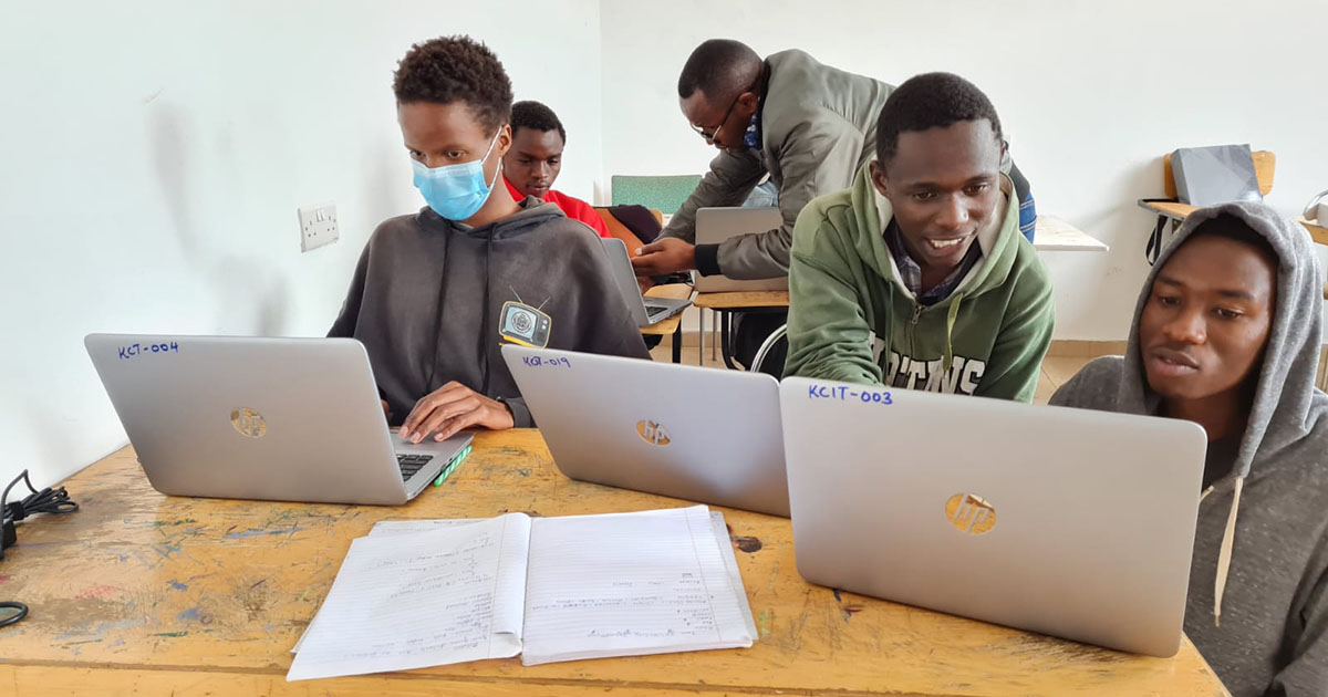 Unga killar programmerar på varsin dator