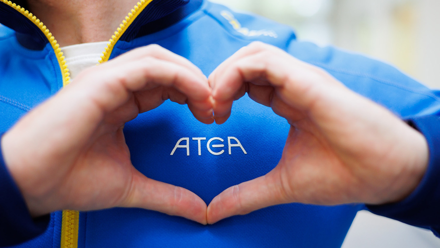 Två händer formar ett hjärta framför Ateas logotyp