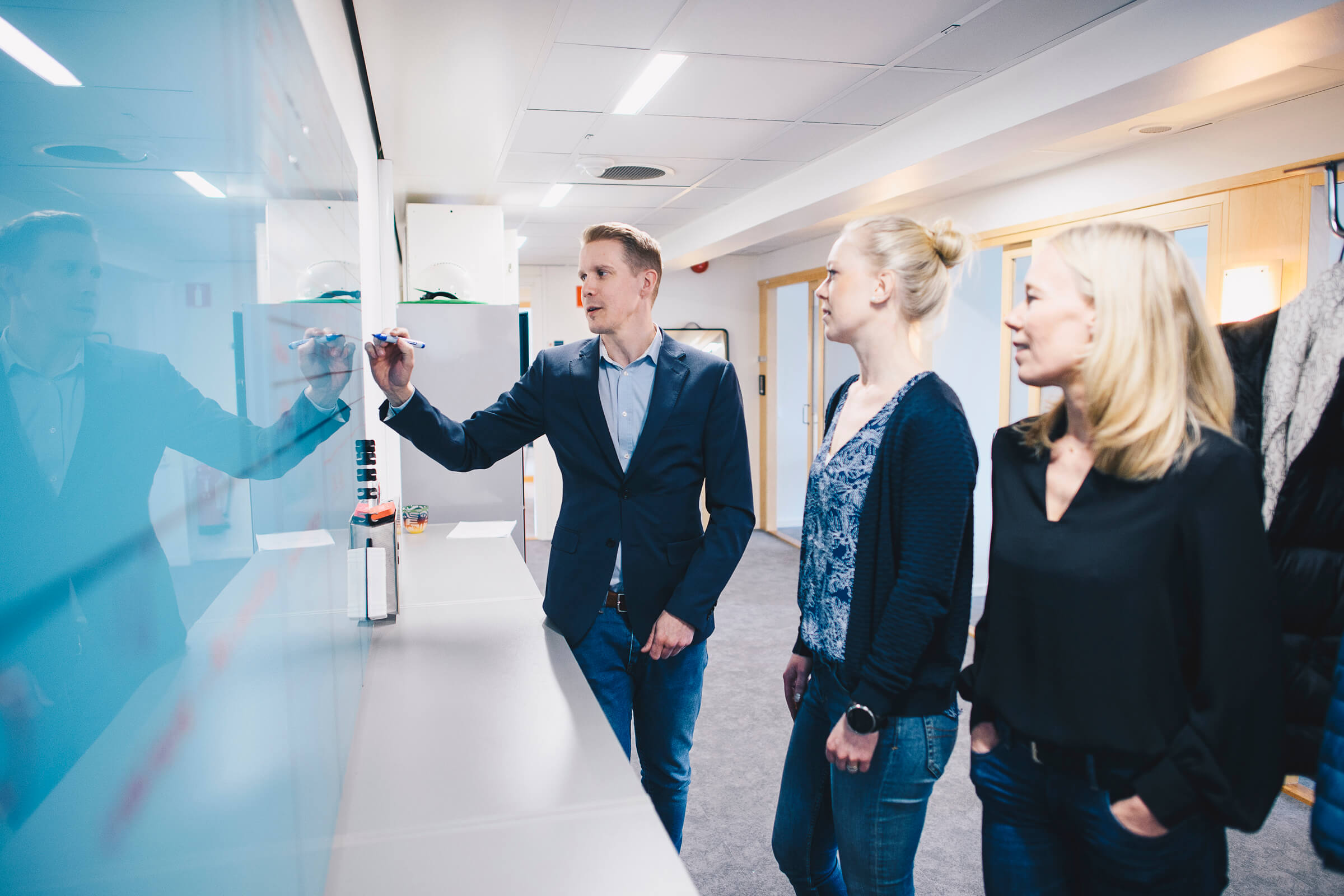 Tre personer står och skissar på en whiteboard