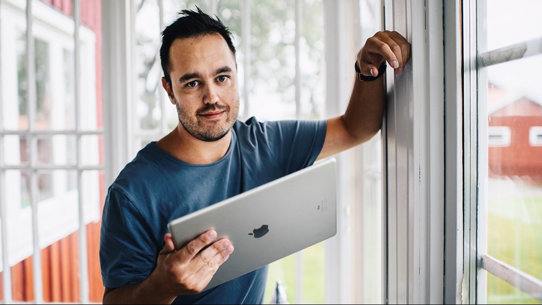 Mikael lutar sig mot fönster och håller en iPad i handel
