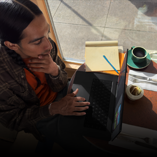 En person som sitter på ett kafé och arbetar på en MacBook Pro som inte är kopplad till elnätet